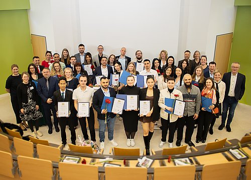 Die ersten Absolventen der generalistischen Pflegeausbildung am PflegeCampus Regensburg halten stolz ihr Examen in den Händen.